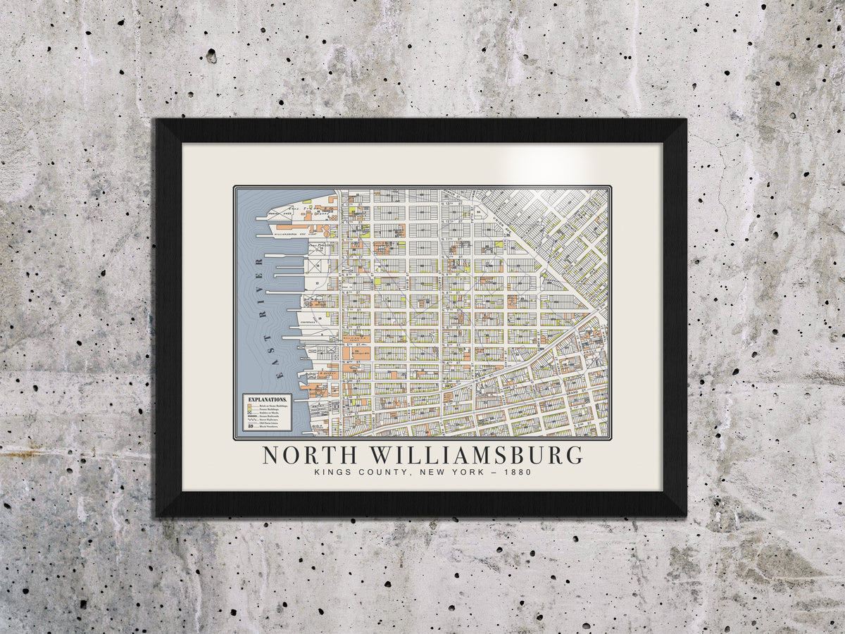 An 1880 archival map of North Williamsburg, Brooklyn, positioned on an unfinished concrete wall. The historical vintage print utilizes a black solid oak frame, adding warmth to a raw, industrial design space.
