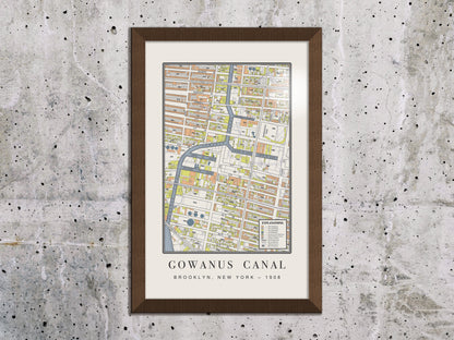 An industrial 1908 map print of the Gowanus Canal in Brooklyn, displayed on a textured raw concrete wall. The archival cartography is housed in a solid oak frame with a dark brown finish, complementing a raw industrial interior.