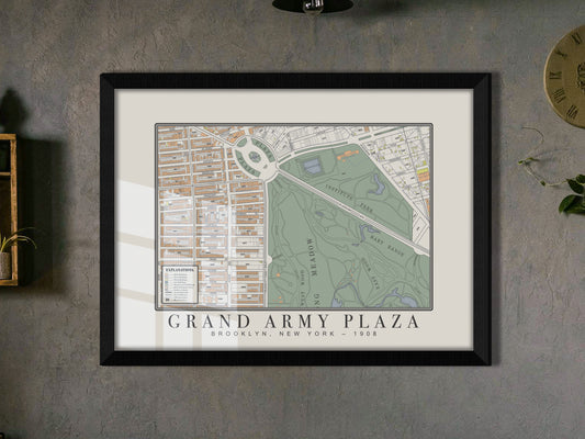 A detailed crop of a 1908 archival map print featuring Grand Army Plaza, Brooklyn. Presented in a black oak frame on a dark grey textured wall, the vintage wall art is accompanied by a rustic shelf and a green trailing plant.